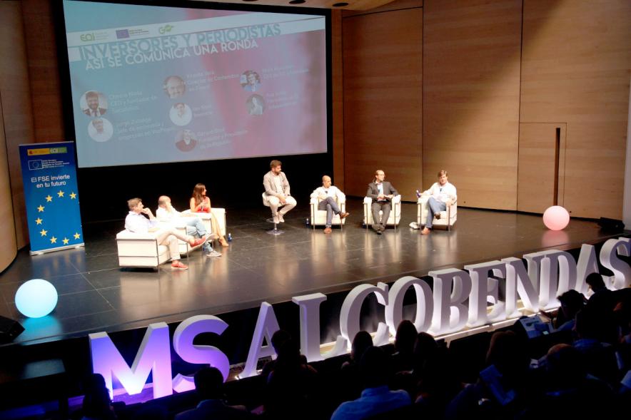 Media StartUps Alcobendas - Imagen del escenario con los ponentes de la presentación y los carteles del evento.