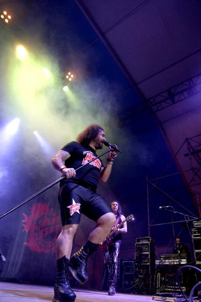 Cantante al micrófono con miembros de la banda al fondo