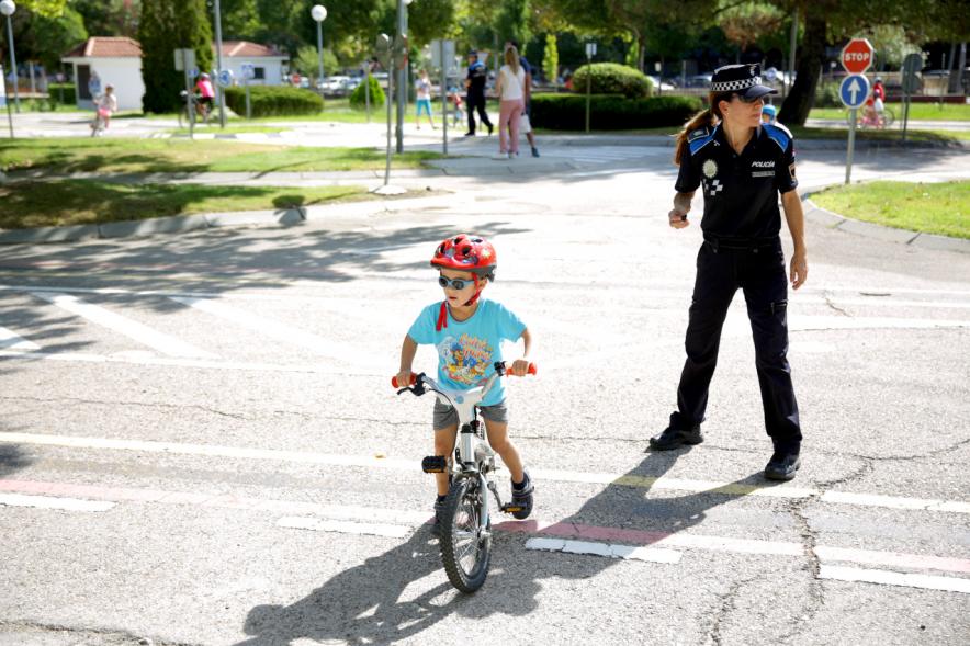 Semana Europea de la Movilidad - Tu Seguridad No Es Un Juego - Imagen de una policía municipal junto a un ciclista infantil.