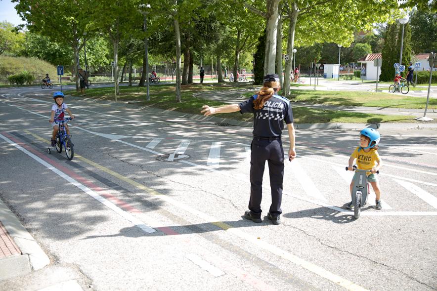 Semana Europea de la Movilidad - Tu Seguridad No Es Un Juego - Imagen de una policía municipal  dirigiendo el tráfico de  ciclistas infantiles.