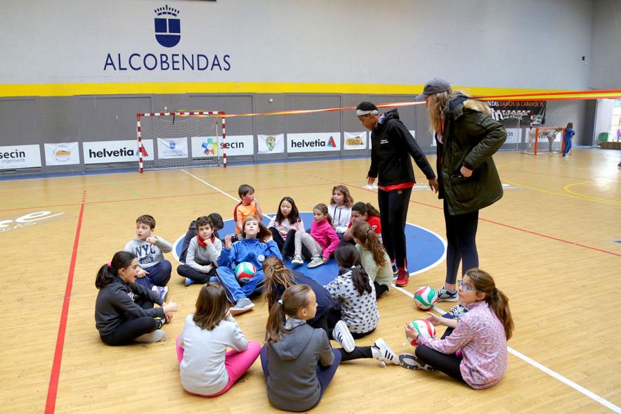Día Multideportivo por la Integración y la Conciliación - Imagen de los  niños sentados en la pista de balonmano con las monitoras.