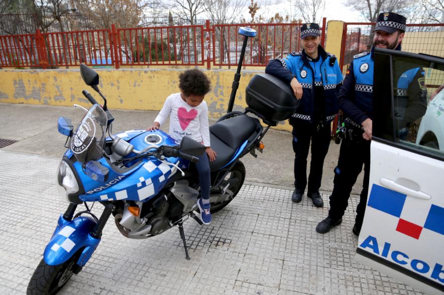 Día Multideportivo por la Integración y la Conciliación -Imagen de dos policías con una niña subida a su moto. 