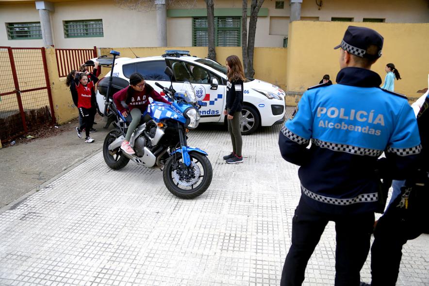 Día Multideportivo por la Integración y la Conciliación -  Un grupo de niños junto a un policía curiosean el coche patrulla y la moto.