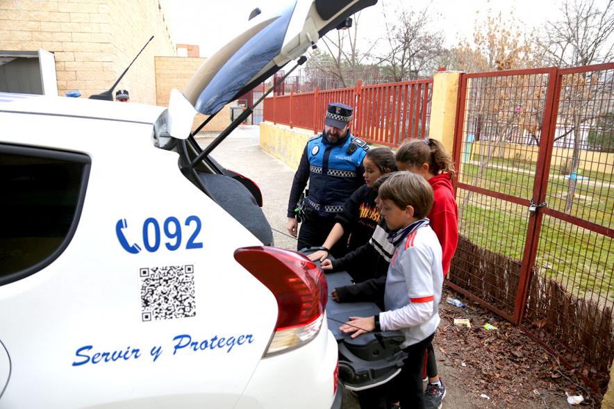 Día Multideportivo por la Integración y la Conciliación - Un grupo de niños junto a un policía curiosean el coche patrulla.