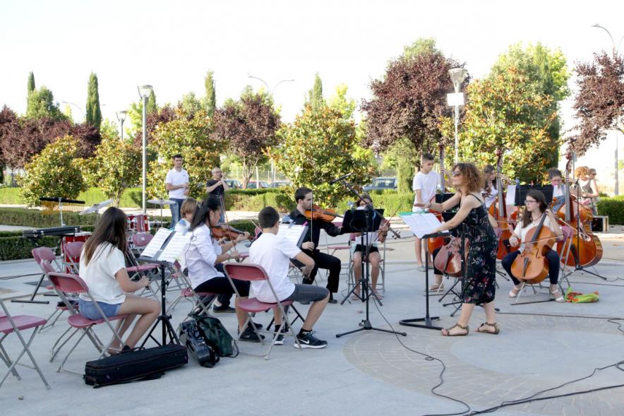 La Música Conquista la Calle - Avda Pablo Iglesias - Imagen de unos jóvenes tocando diferentes instrumentos de cuerda y una directora de orquesta que les dirige.