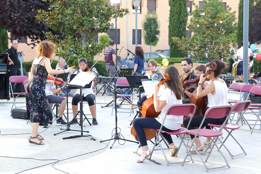 La Música Conquista la Calle - Avda Pablo Iglesias - Imagen de unos jóvenes tocando diferentes instrumentos de cuerda y una directora de orquesta que les dirige.