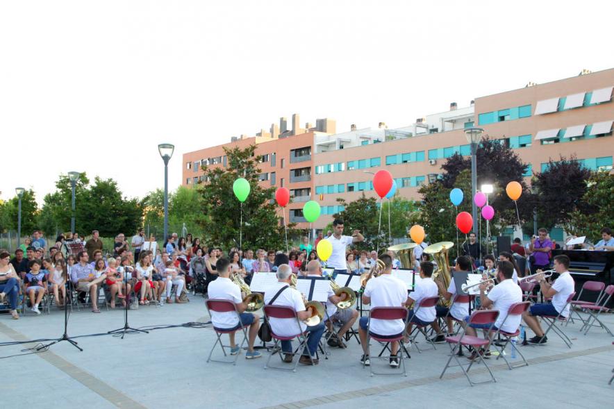 La Música Conquista la Calle - Avda Pablo Iglesias - Imagen de unos jóvenes tocando diferentes instrumentos de viento y una directora de orquesta que les dirige y además vemos globos de colores.