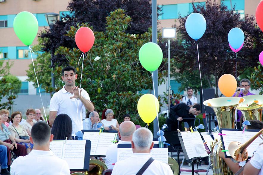 La Música Conquista la Calle - Avda Pablo Iglesias - Imagen de unos jóvenes tocando diferentes instrumentos de viento y una directora de orquesta que les dirige y además vemos globos de colores.