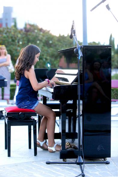La Música Conquista la Calle - Avda Pablo Iglesias - Imagen de unos jóvenes tocando diferentes instrumentos de viento y una directora de orquesta que les dirige .