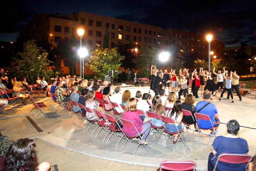 La Música Conquista la Calle - Avda Pablo Iglesias - Imagen de público asistente al evento y unos jóvenes en el escenario, donde se están haciendo una especie de danza y les dirige una persona.
