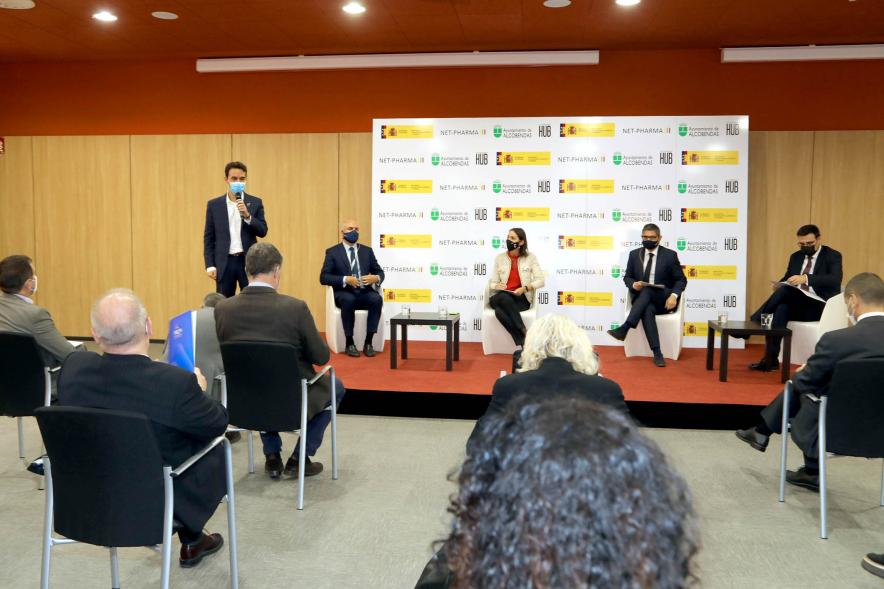 Visita de la Ministra de Industria, Comercio y Turismo a NetPharma - Imagen general de la mesa de ponentes con la ministra Maroto, el alcalde Sánchez Acera y el vice alcalde Arranz,  frente a un numeroso grupo sentado  de  la firma NetPharma.
