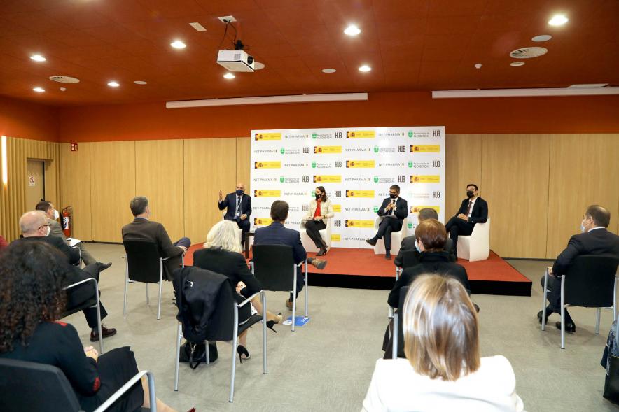Visita de la Ministra de Industria, Comercio y Turismo a NetPharma - Plano general de la sala de reuniones con  miembros de la empresa y la ministra Maroto y la corporación municipal de Alcobendas sentados al frente.