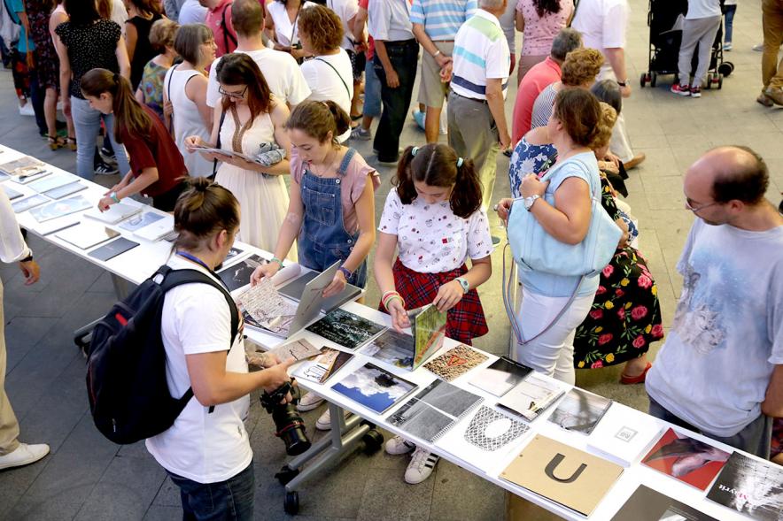 Noche en Blanco 2018 - Imagen de personas reunidas en la entrada del Centro de Arte...mirando las mesas con objetos expuestos.