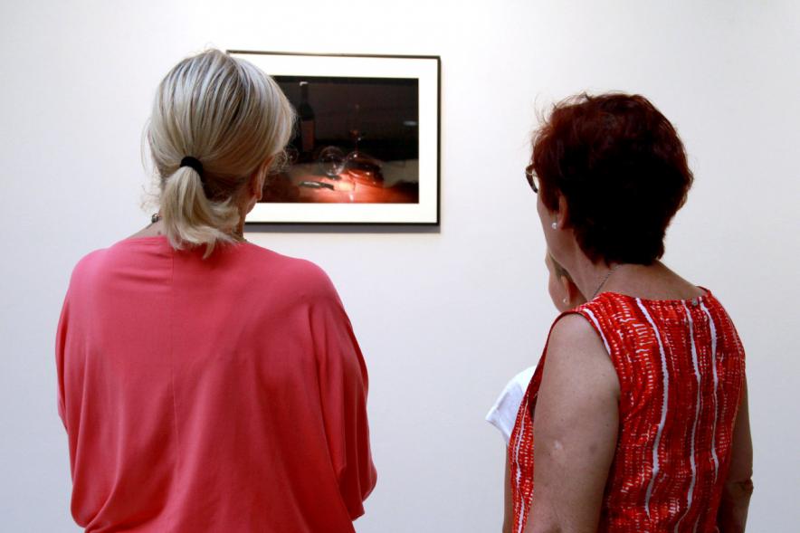 Inauguración Exposición "Objetos Iluminados" de A Contraluz - Imagen de personas admirando una fotografía de la exposición.