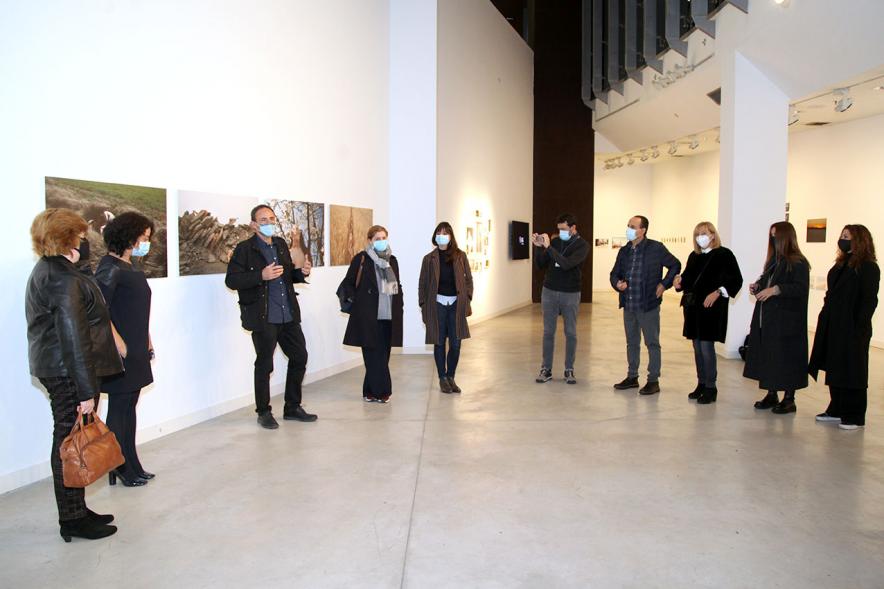 Inauguración Exposición "Encuentros en Tiempo Presente" - Master PIC.A - Imagen de los organizadores comentando la exposición y  parte de los  visitantes, en círculo, con mascarilla.