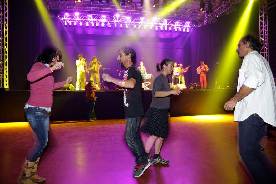 Gala a Favor de la Asociación Enfermos de Parkinson ALCOSSE - Imagen de personas bailando, mientras en el escenario actúa un grupo de música.