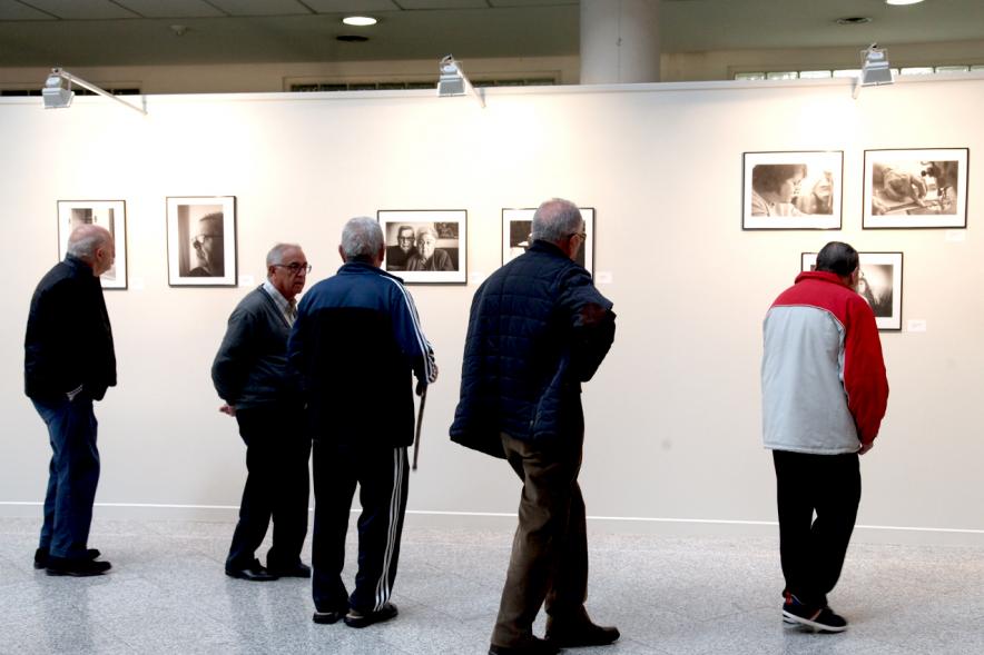 Inauguración Fotográfica sobre el Parkinson en el Patio de Encuentros - Imagen de personas mirando la exposición.