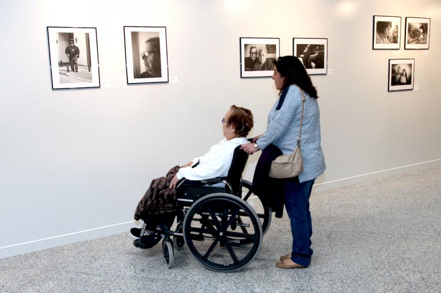 Inauguración Fotográfica sobre el Parkinson en el Patio de Encuentros - Imagen de personas mirando la exposición.