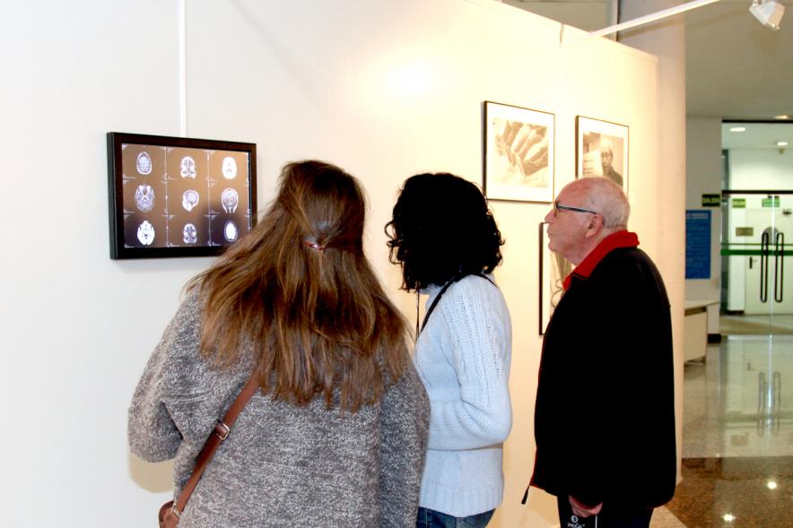 Inauguración Fotográfica sobre el Parkinson en el Patio de Encuentros - Imagen de personas mirando la exposición.