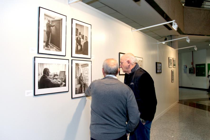 Inauguración Fotográfica sobre el Parkinson en el Patio de Encuentros - Imagen de personas mirando la exposición.