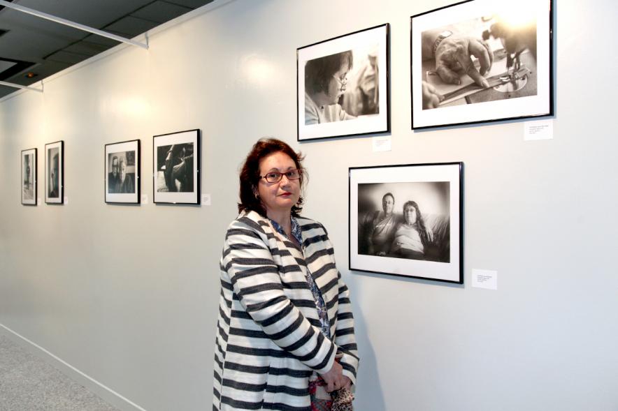 Inauguración Fotográfica sobre el Parkinson en el Patio de Encuentros - Imagen de una mujer posando delante de una de las fotografías.