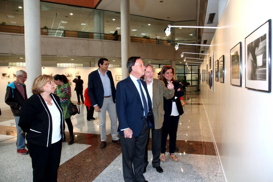 Inauguración Fotográfica sobre el Parkinson en el Patio de Encuentros - Imagen del autor Carlos Carneiro y el alcalde García de Vinuesa y otras personas recorriendo la exposición.