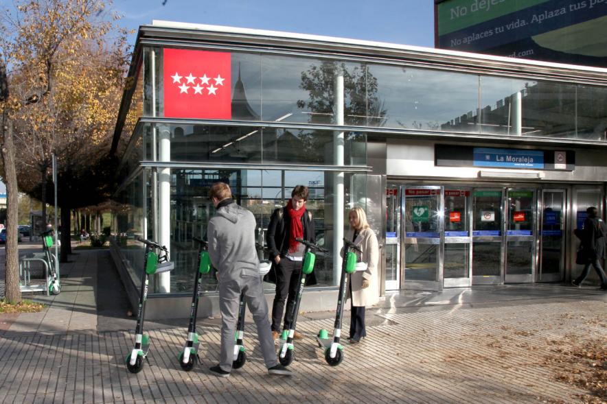 Presentación Patinetes Eléctricos Empresa LIme España - Imagen en primer plano tenemos unos patinetes aparcados en la calle y personas mirándolos.