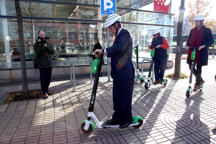 Presentación Patinetes Eléctricos Empresa LIme España - Imagen del alcalde García de Vinuesa montado en un patinete, seguido de otras autoridades.