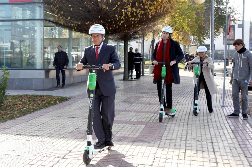Presentación Patinetes Eléctricos Empresa LIme España - Imagen del alcalde García de Vinuesa montado en un patinete, seguido de otras autoridades.