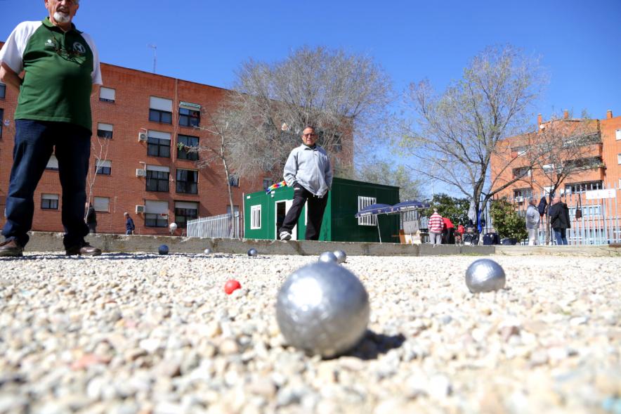 Primer plano de bola de petanca en campo de juego con jugadores al fondo