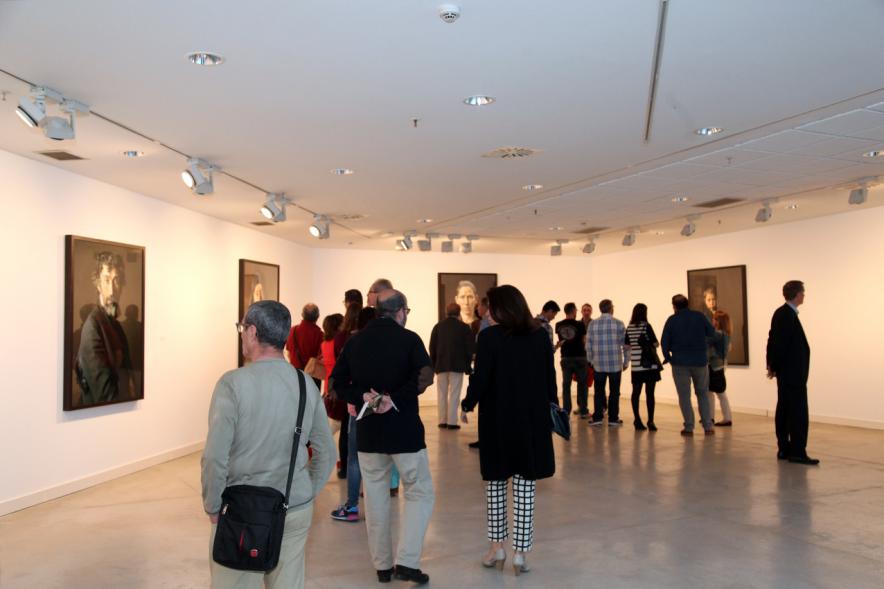 Plano abierto de visitantes a la galería con fotos al fondo