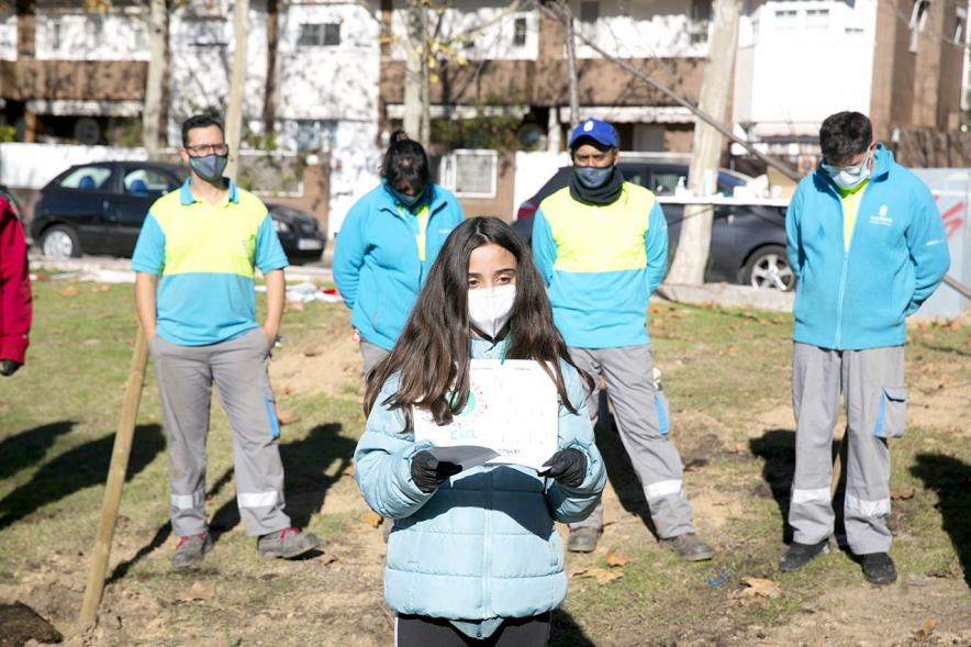 Plantación de Árboles por parte de Niños y Niñas del Consejo de la Infancia -  Plano central de una joven leyendo un manifiesto rodeada de jardineros.