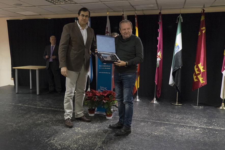 Entrega de Premios del XVº Certamen de Poesía de las Casas Regionales - Imagen de persona entregando una placa a un homenajeado.