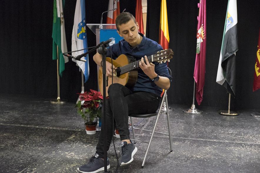 Entrega de Premios del XVº Certamen de Poesía de las Casas Regionales - Imagen de persona tocando la guitarra en el escenario.