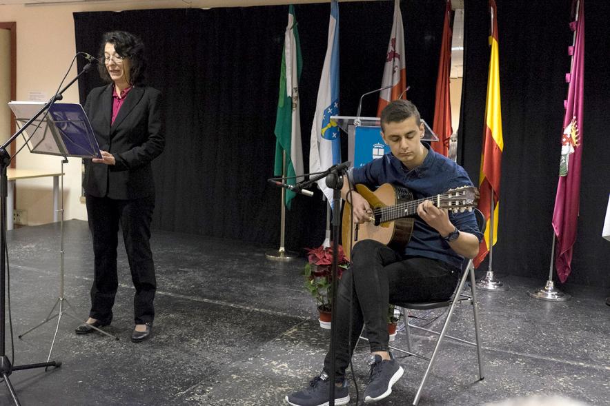 Entrega de Premios del XVº Certamen de Poesía de las Casas Regionales - Imagen de persona tocando la guitarra y alguien recitando en el escenario.