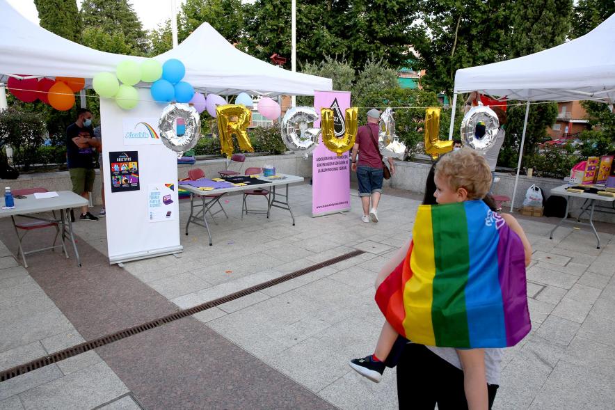 Pregón Día del Orgullo 2021 - Imagen de los puestos de venta y una madre con su hijo llevando la bandera.