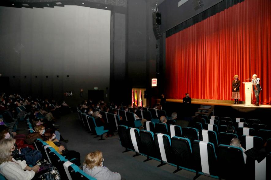 Entrega de Premios Atenea y Hombres por la Igualdad 2021 - Imagen del auditorio, con las medidas de seguridad. En el escenario iluminado el premiado y la concejal de  Igualdad.