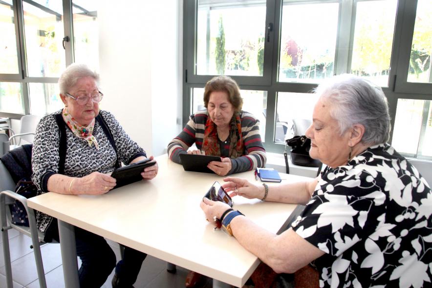 Presentación Proyecto Piloto Familyar Social Service - Imagen de unas personas mayores probando el dispositivo que se esta presentando en el acto.