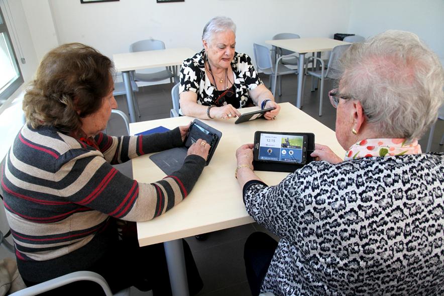 Presentación Proyecto Piloto Familyar Social Service -  Imagen de unas personas mayores probando el dispositivo que se esta presentando en el acto.