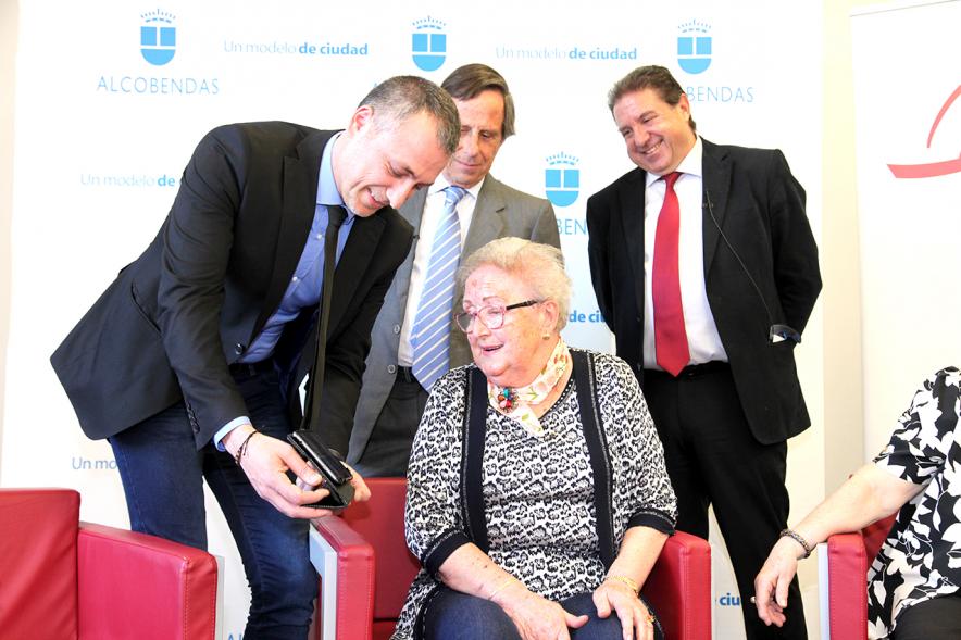 Presentación Proyecto Piloto Familyar Social Service - Imagen de una persona mayor recibiendo el dispositivo que se esta presentando en el acto.