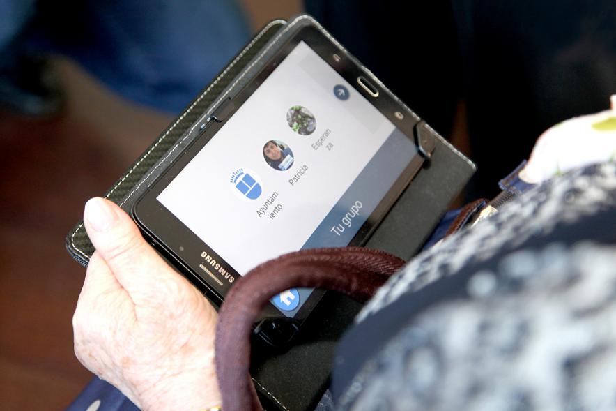Presentación Proyecto Piloto Familyar Social Service - Imagen de una persona mayor probando el dispositivo que se esta presentando en el acto.