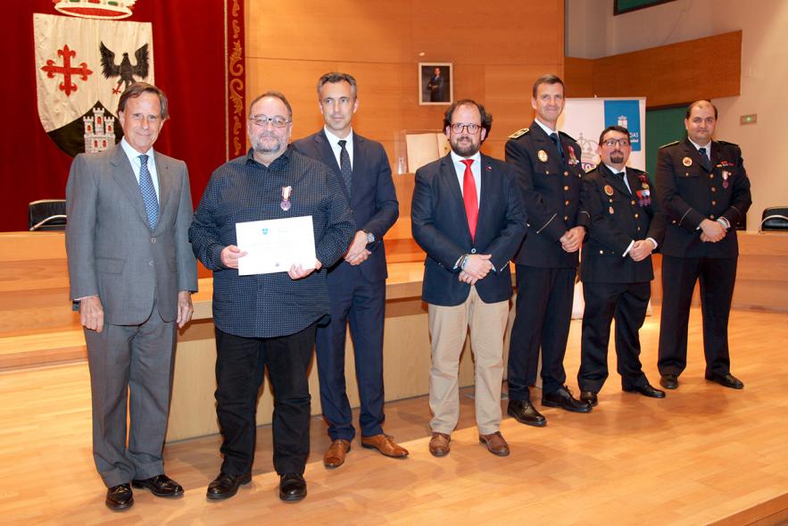 Entrega de Medallas de Protección Civil 2018 -  Imagen de una persona posando con su medalla y su diploma posando junta a las autoridades que se lo han entregado, entre ellas el alcalde García de Vinuesa.