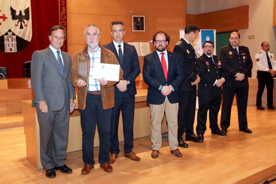 Entrega de Medallas de Protección Civil 2018 -   Imagen de una persona posando con su medalla y su diploma posando junta a las autoridades que se lo han entregado, entre ellas el alcalde García de Vinuesa.