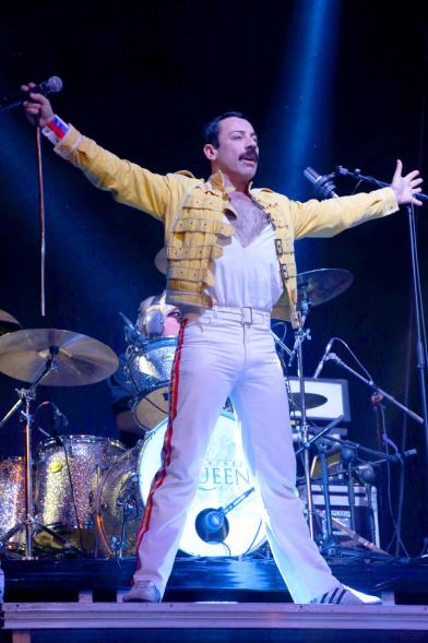 Cantante con los brazos abiertos durante el concierto con la indumentaria de Freddie Mercury