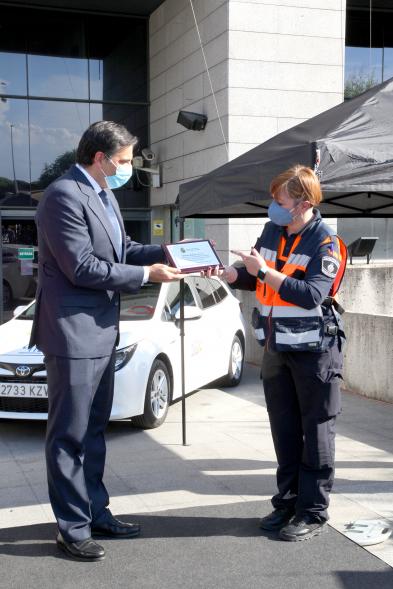 Entrega Reconocimiento a Toyota por Protección Civil de Madrid -Imagen de Miguel Carsi, CEO de Toyota, con mascarilla, entregando una placa a una voluntaria de Protección Civil. 