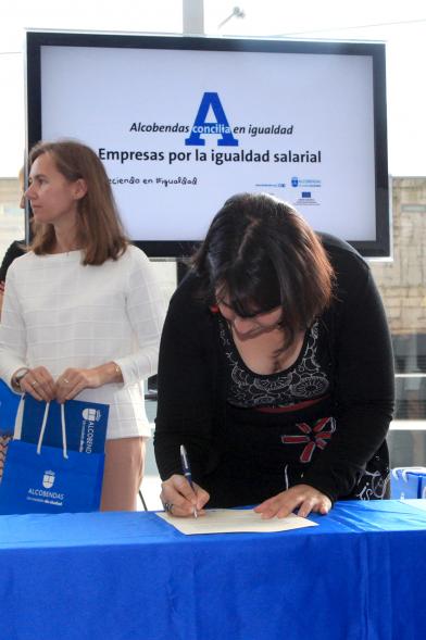 Reconocimiento a Empresas por Igualdad Salarial y Alcobendas Concilia - Persona asistente al acto firmando unos documentos.