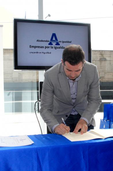Reconocimiento a Empresas por Igualdad Salarial y Alcobendas Concilia - Persona asistente al acto firmando unos documentos.