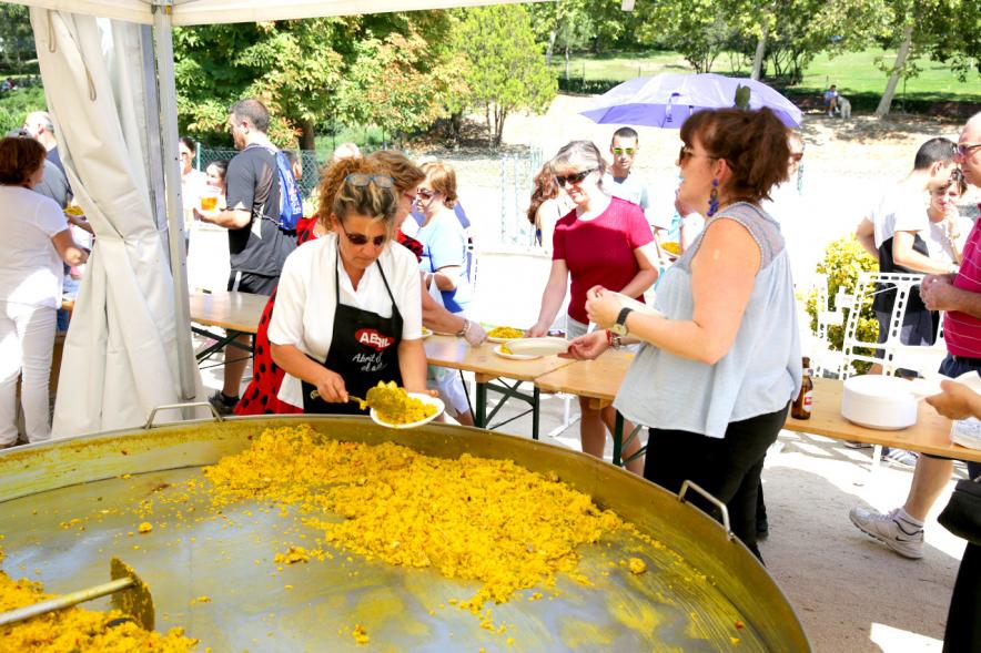 Paellada popular con detalle de mujer sirviendo un plato