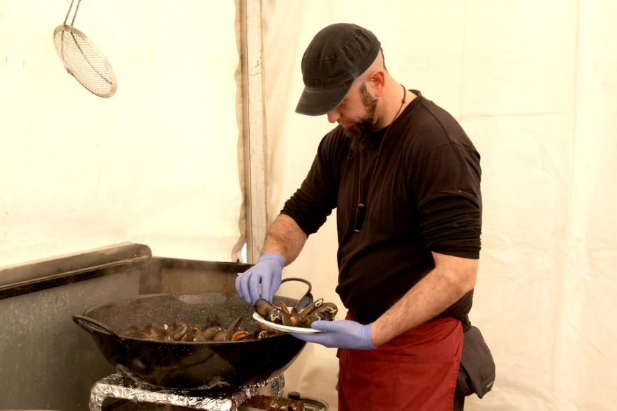 XXIIª Feria del Pulpo y el Mejillón - Imagen de persona preparando una ración de mejillones.