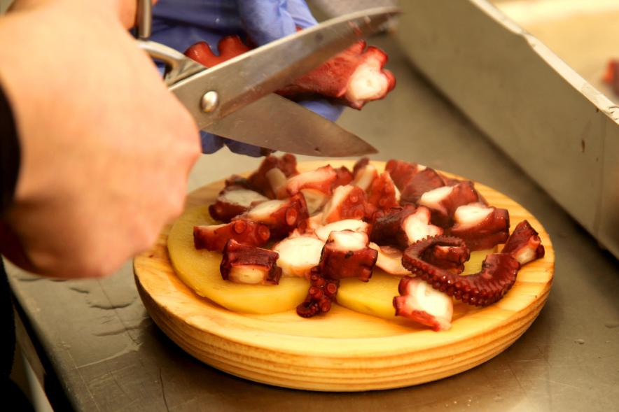 XXIIª Feria del Pulpo y el Mejillón - Imagen de unas manos con unas tijeras cortando el pulpo para un plato de "pulpo a feira".